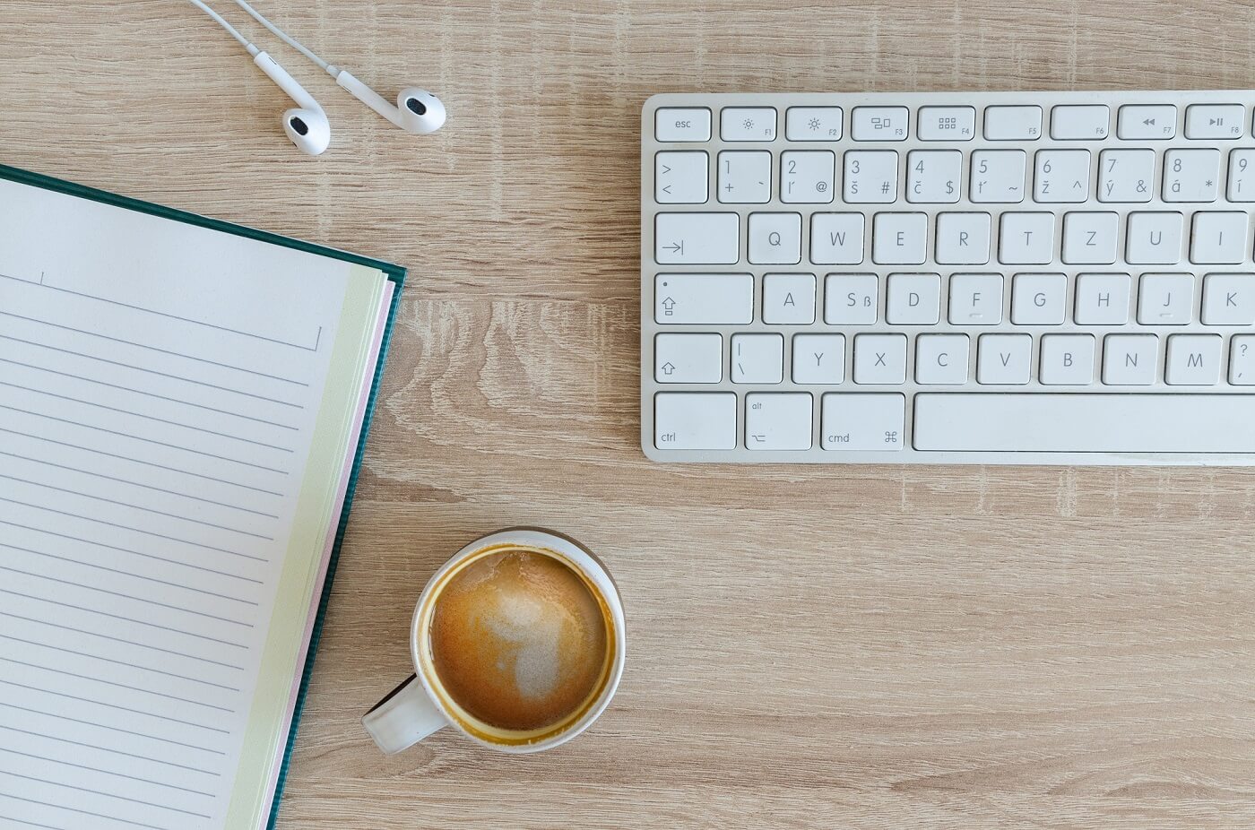 foto de um teclado, notebook e xícara de café